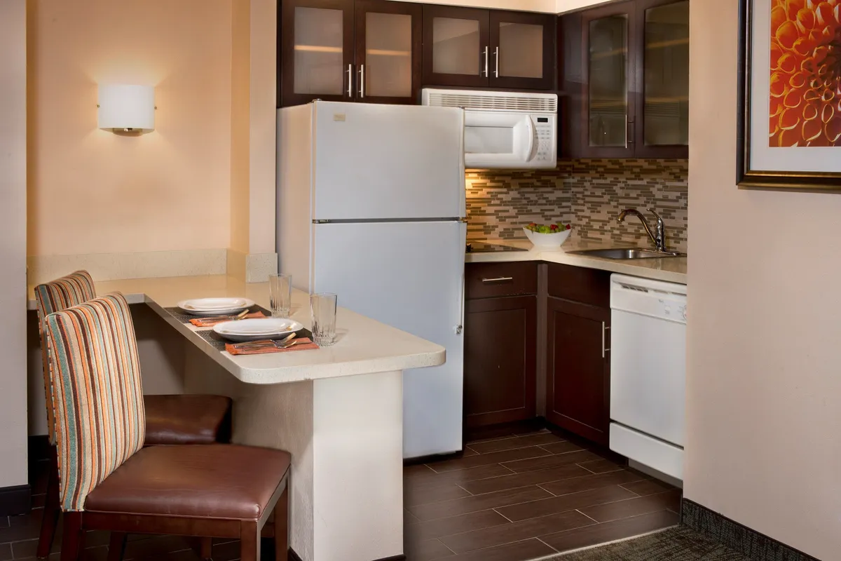 A thoughtfully equipped living area with kitchen appliances, ample counter space, a dining area, and colorful upholstered chairs. The setup is inviting for cooking, casual dining, or socializing with guests.
