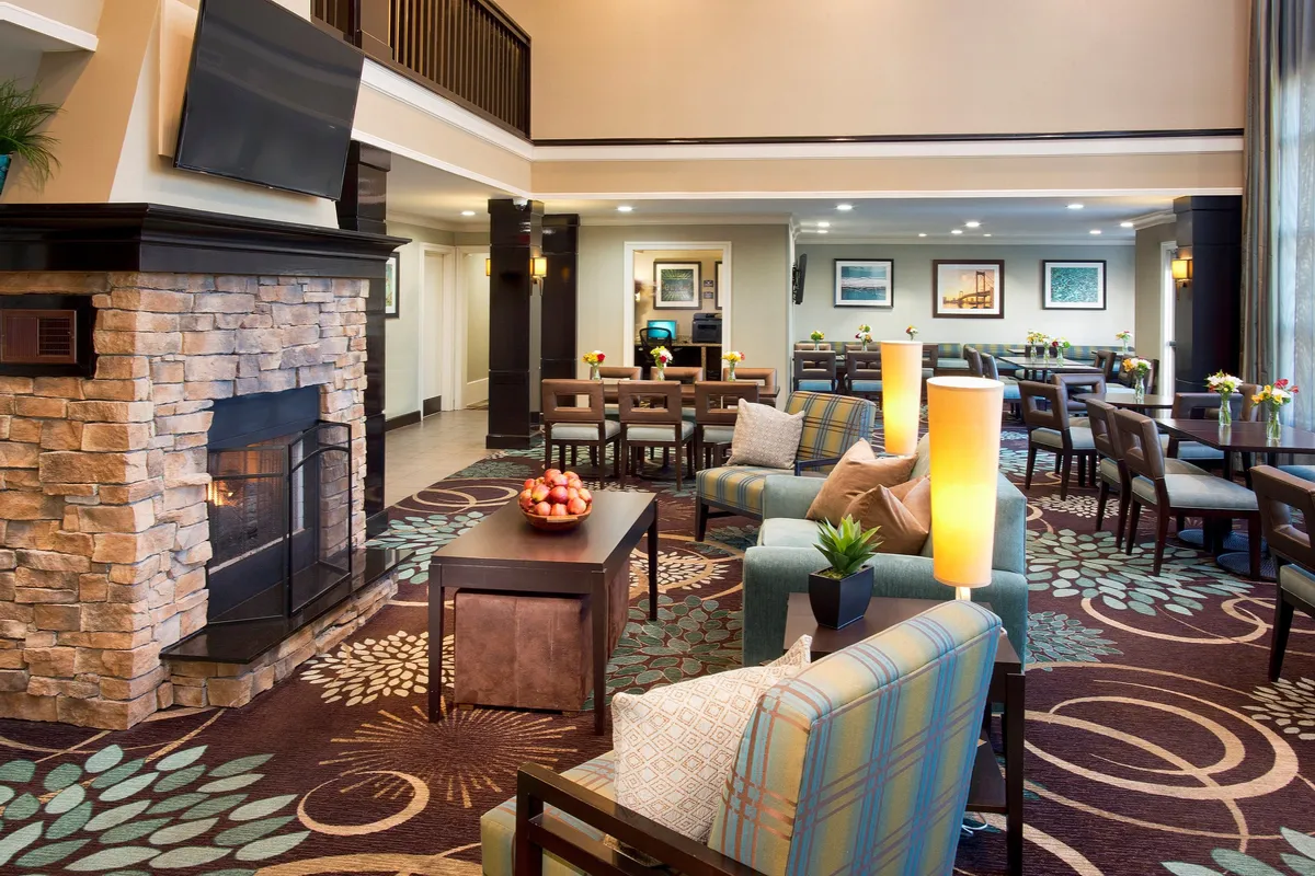 A welcoming seating area arranged around a fireplace, accented by decorative plants and vibrant artwork. The setting is inviting for socializing, quiet moments, or watching TV, radiating comfort and warmth.