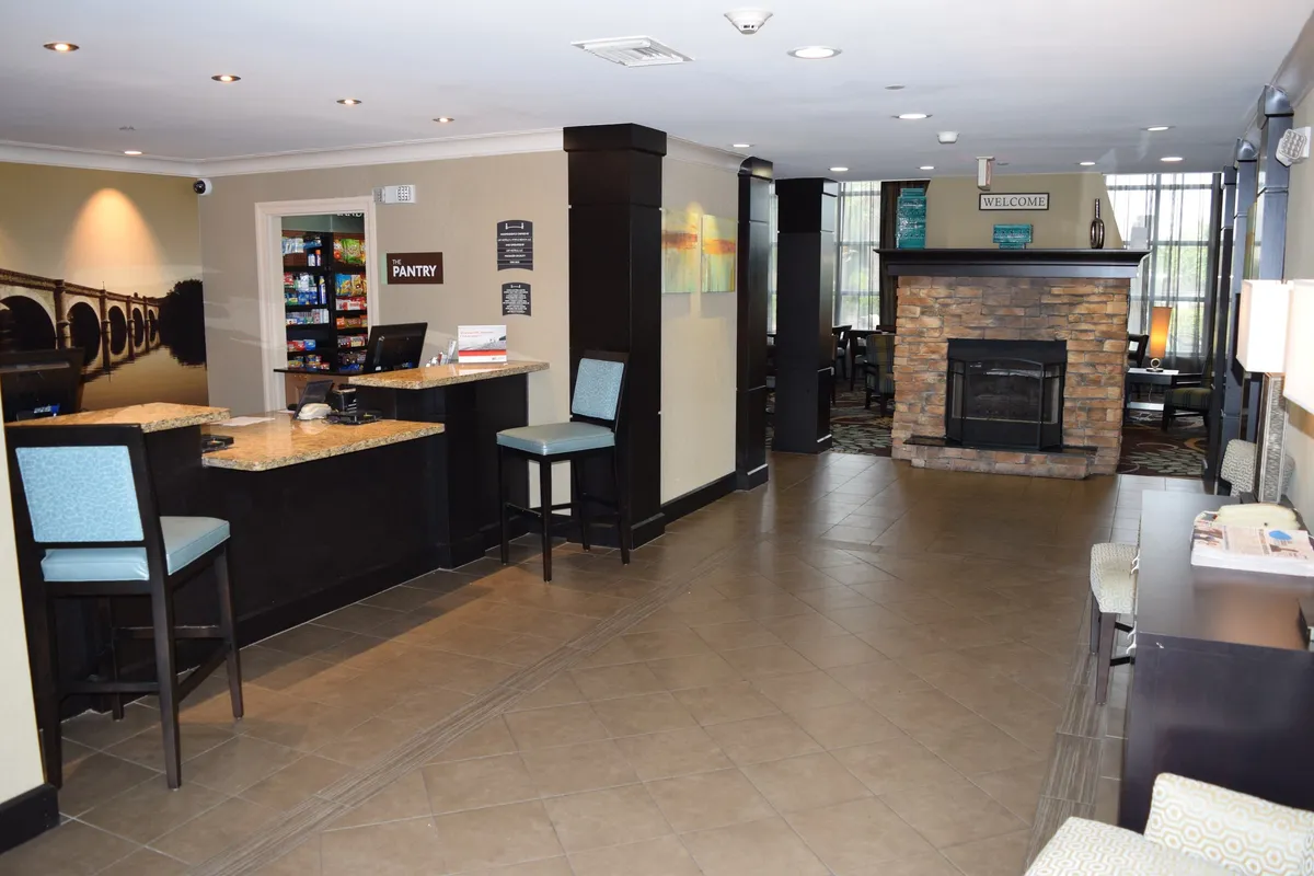 A welcoming interior featuring the front desk, comfortable seating area with a fireplace, and a nearby pantry. The space feels inviting and warm—ideal for relaxing or socializing before or after work.